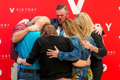 Members embracing together at the Victory photo wall
