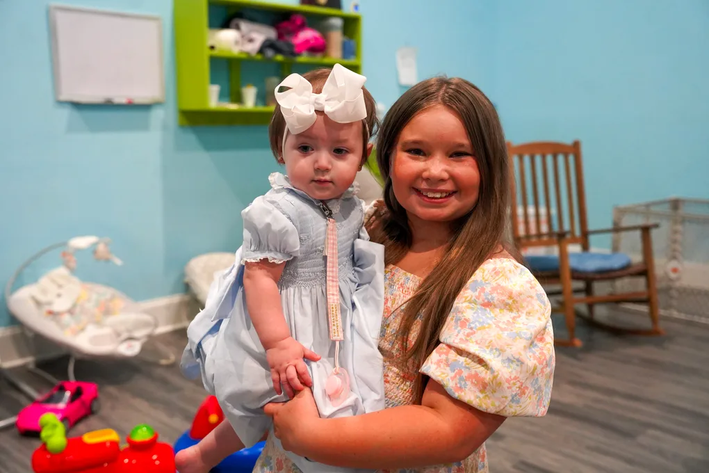 A girl holding a baby in the nursery
