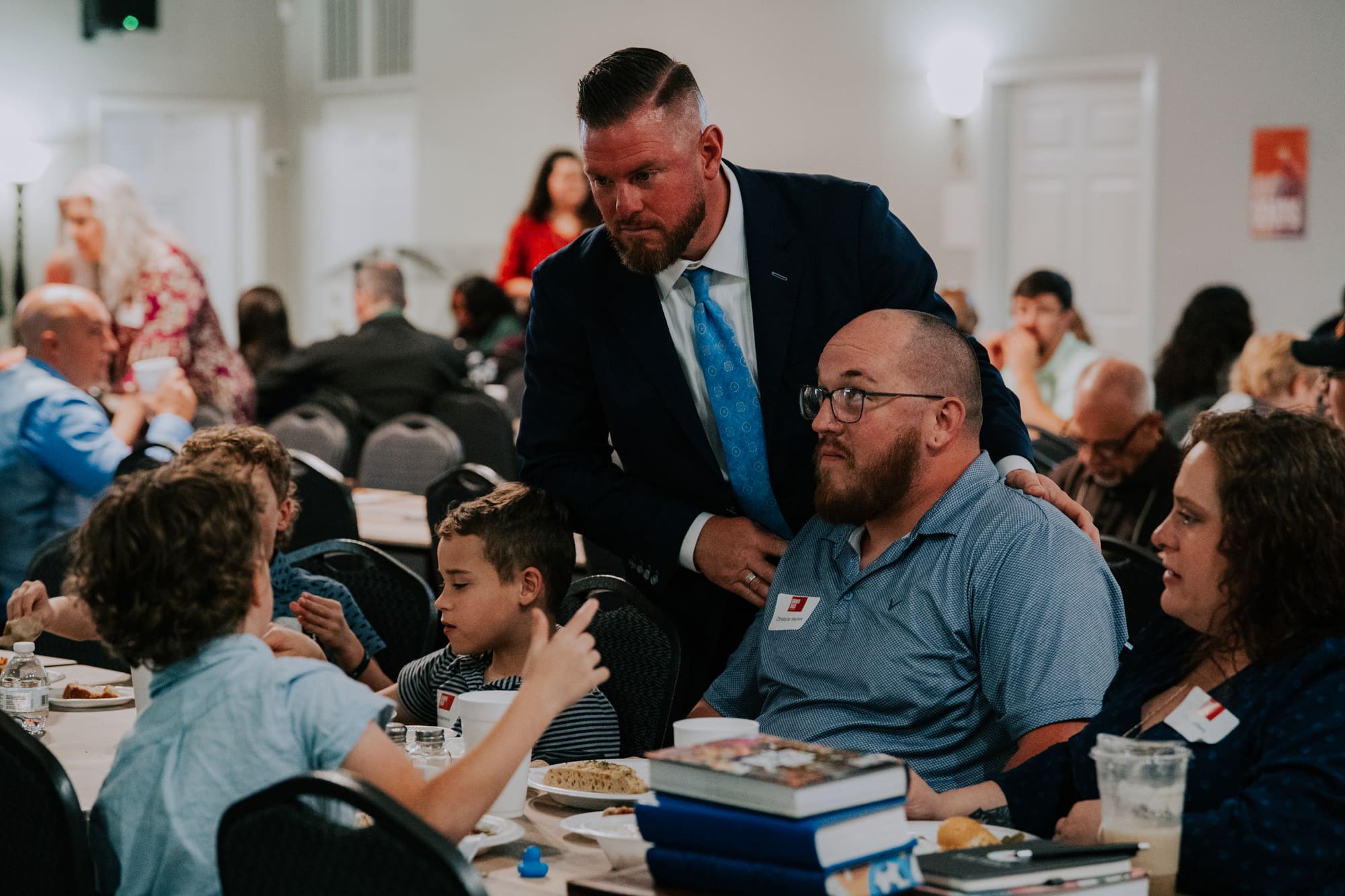 A pastor crouched beside a family at their table during a Growth Track meal