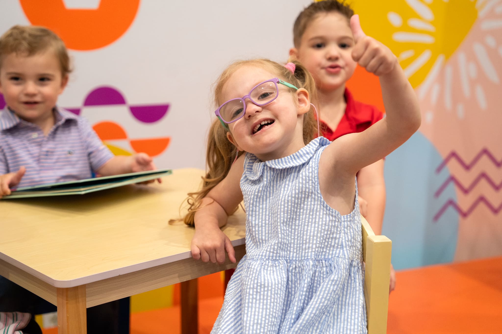 Kids at a table in the Victory Kids room, one giving a thumbs-up